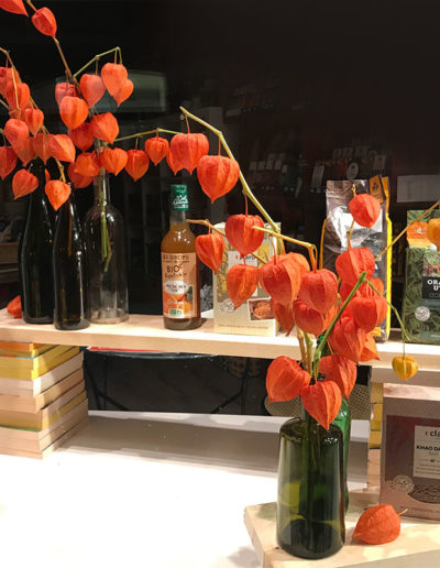 Une vitrine d’automne avec des physalis et des livres recyclés